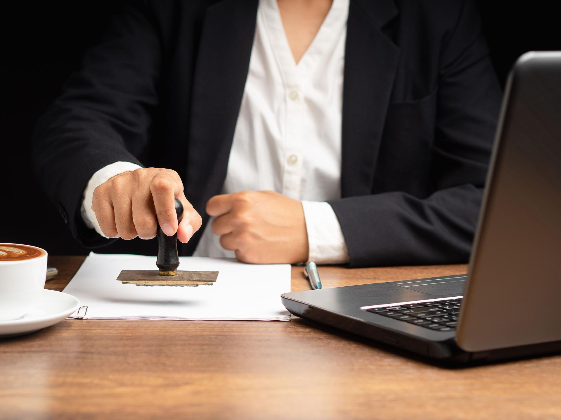 Businesswoman stamping approved on documents while sitting working in the office